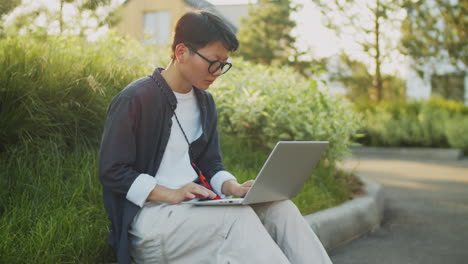 Retrato-De-Una-Alegre-Mujer-Asiática-Trabajando-En-Una-Computadora-Portátil-En-La-Calle