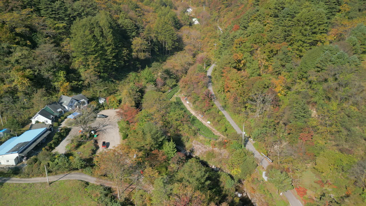 A reverse view moving away from a resthouse, showing a beautiful mountain valley filled with dense autumn colors