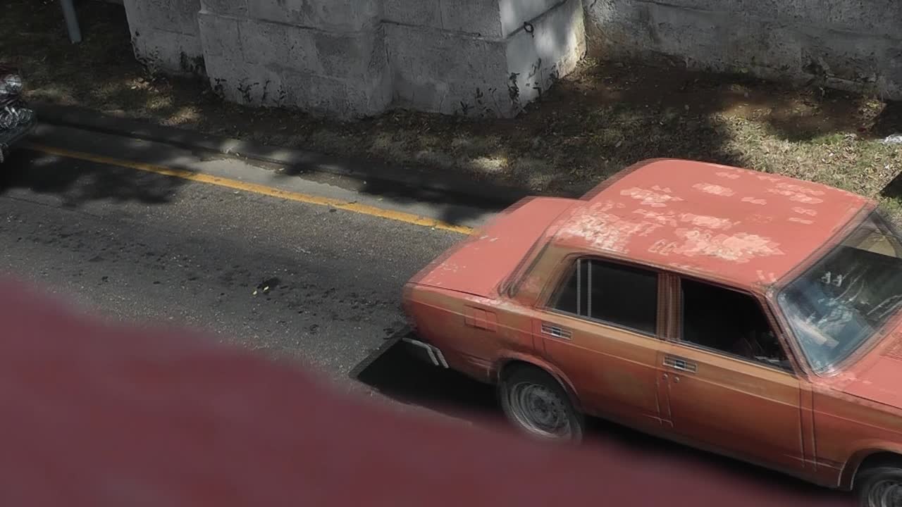 View from balcony down on city street of Havana where typical and colorful cuban vintage cars and taxis are passing by one after another
