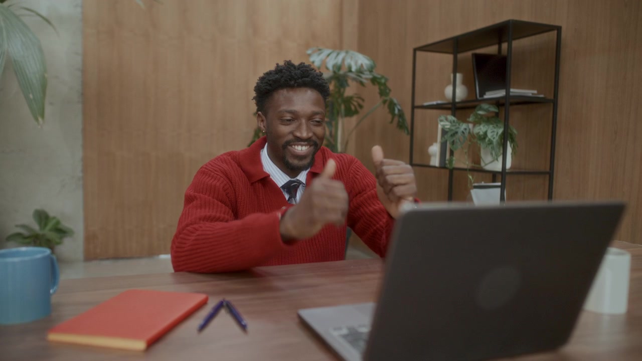 Uomo d'affari nero sorridente che parla alla webcam del laptop durante una videochiamata