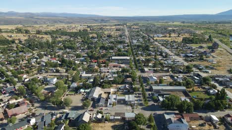 aerial dolly in flying above trevelin valley houses with andean mountains in background, patagonia argentina