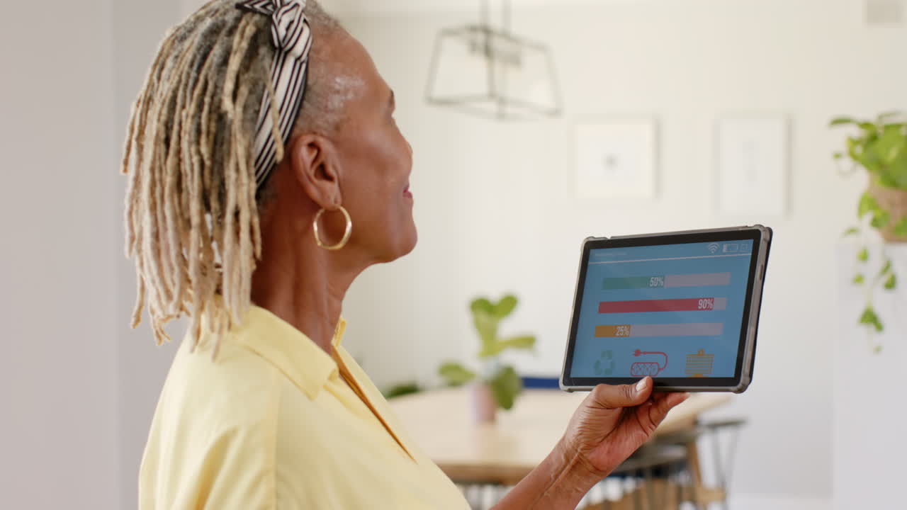 A senior African American woman with braided hair is holding tablet