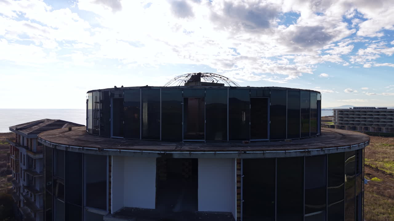 Round roof of the building of cylinder shape. Drone footage of the construction sit against cloudy sky