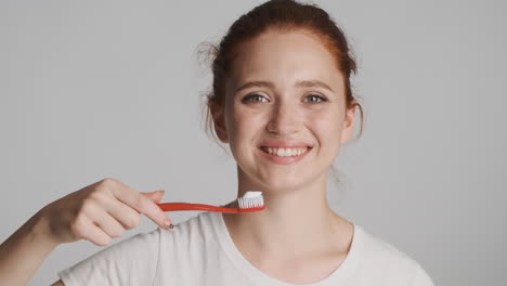 redheaded girl in front of camera on gray background.