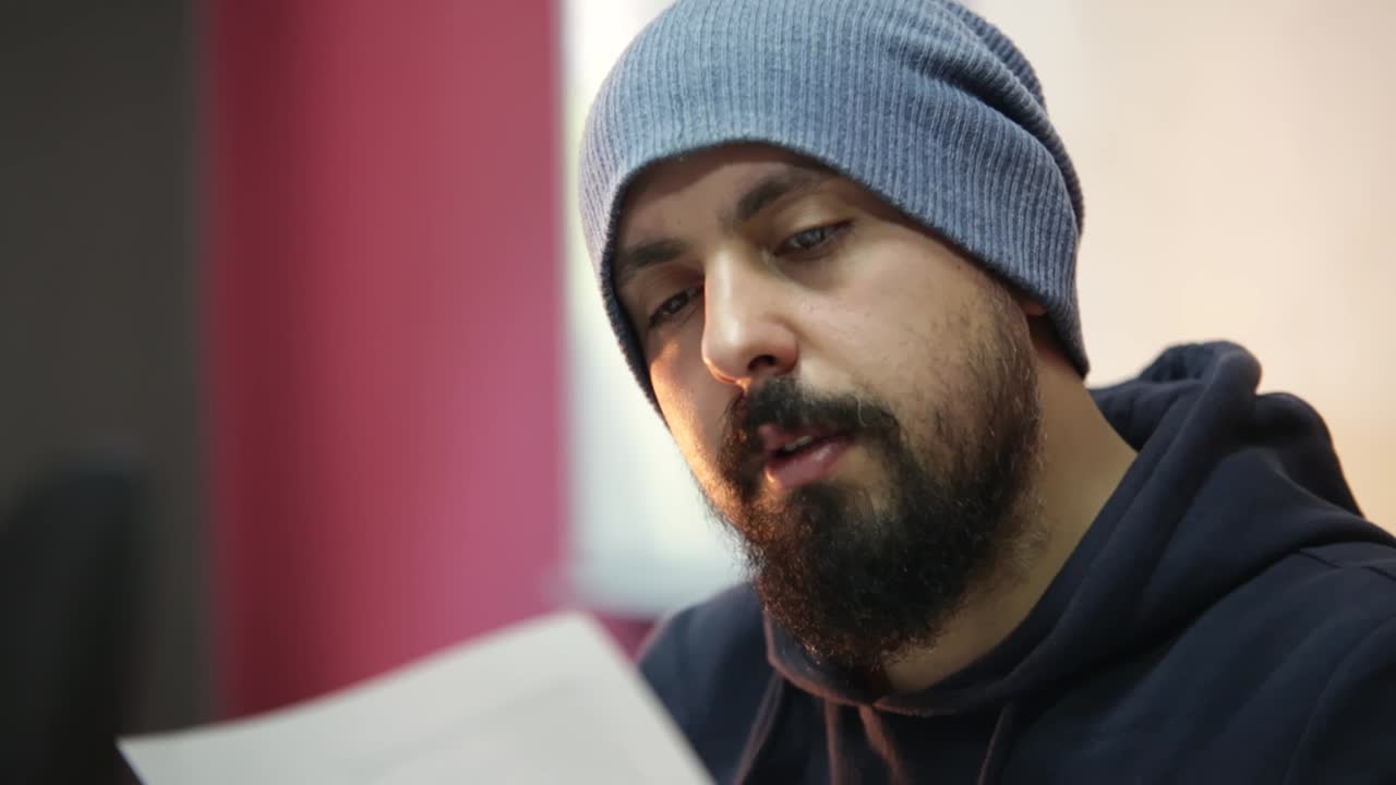 Bereli, genç, sakallı ve şık bir adam, ofis arkadaşlarının teklifini okurken, yeni fikri şüpheyle başını sallayarak onaylıyor.