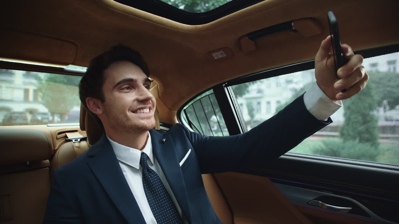 hombre de negocios sonriente haciendo una foto selfie en el teléfono inteligente en el coche de negocios.