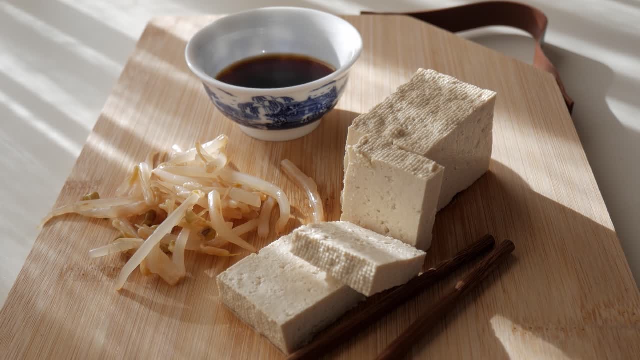 Tofu with soy sauce and sprouts on wooden board, peaceful morning light