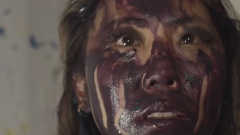 the female model poses on a white backdrop covered in dark paint