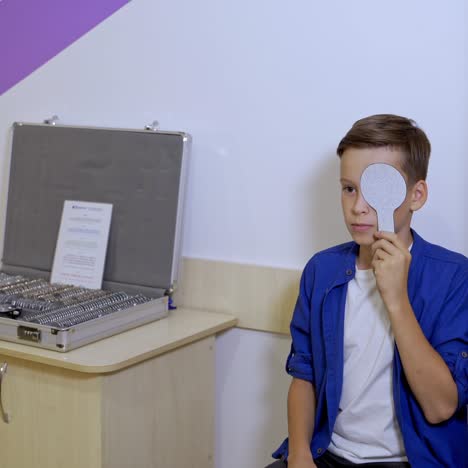 portrait of handsome boy checking eyesight. professional ophthalmologist checks the eyesight of the child. eye examination