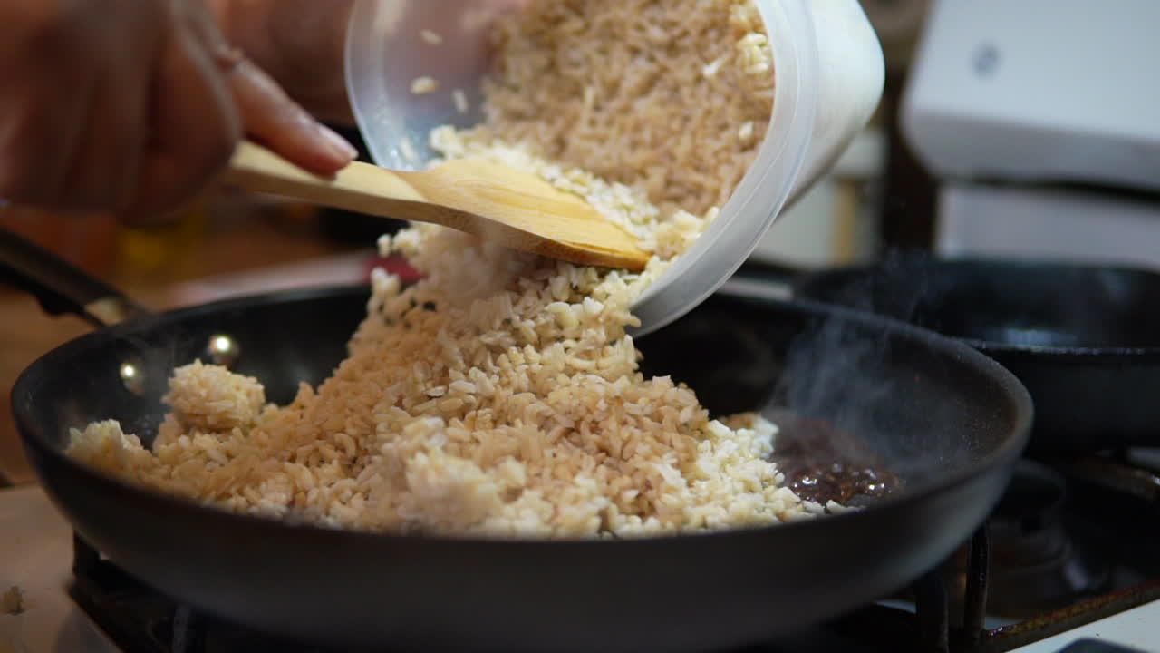 agregando arroz al vapor a una sartén para hacer arroz frito - cámara lenta