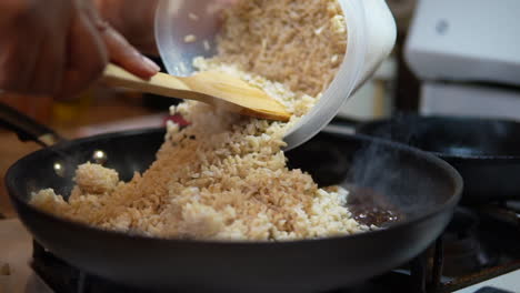 Adding-steamed-rice-to-a-skillet-to-make-fried-rice---slow-motion