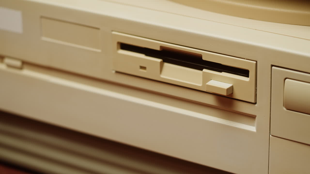 Hand inserting a floppy disk into a vintage computer
