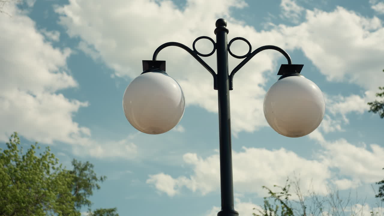 Farola urbana intrincada con fondo nuboso, farola artística de metal bajo un cielo tormentoso con nubes, farola elegante vintage con globos gemelos sobre un cielo nuboso y sombrío