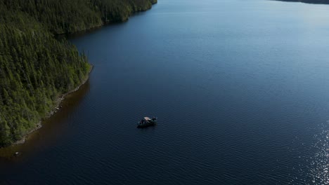 Drone-flying-from-a-fishing-boat-and-soars-high-in-the-sky-to-reveal-the-expanse-of-a-beautiful-lake