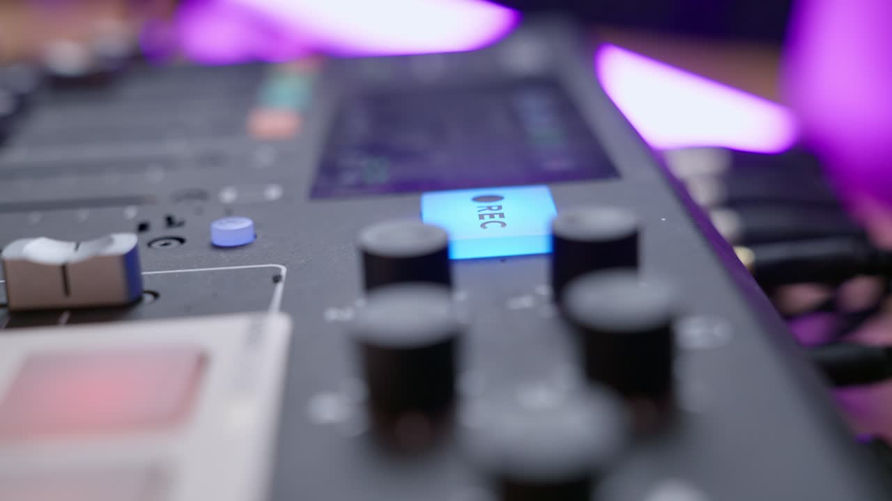 Hand pushes button to begin recording in audio booth or professional sound studio. Engineer clicking on REC button on audio console or mixer during live streaming show or radio session