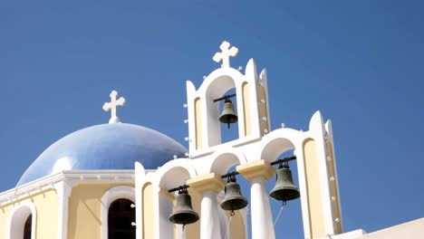 zoom in on a church dome and four bells in fira, santorini