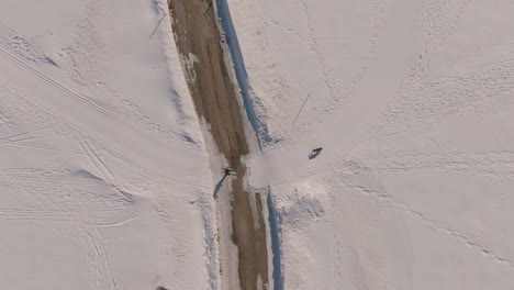 Aerial-Drone-shot-of-a-man-cross-country-skiing-with-his-dog-crosses-a-road----Orbit-Shot