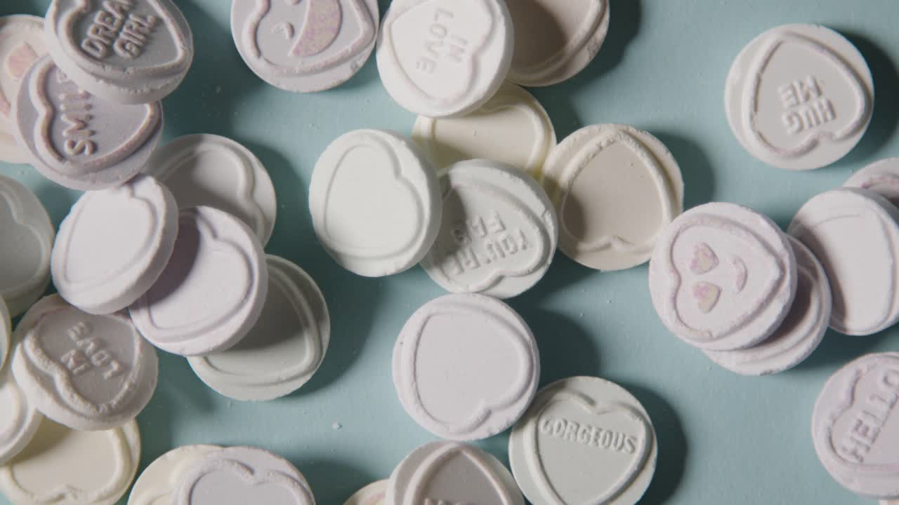 파란색 배경에 던져진 낭만적인 사랑의 메시지가 담긴 하트 캔디