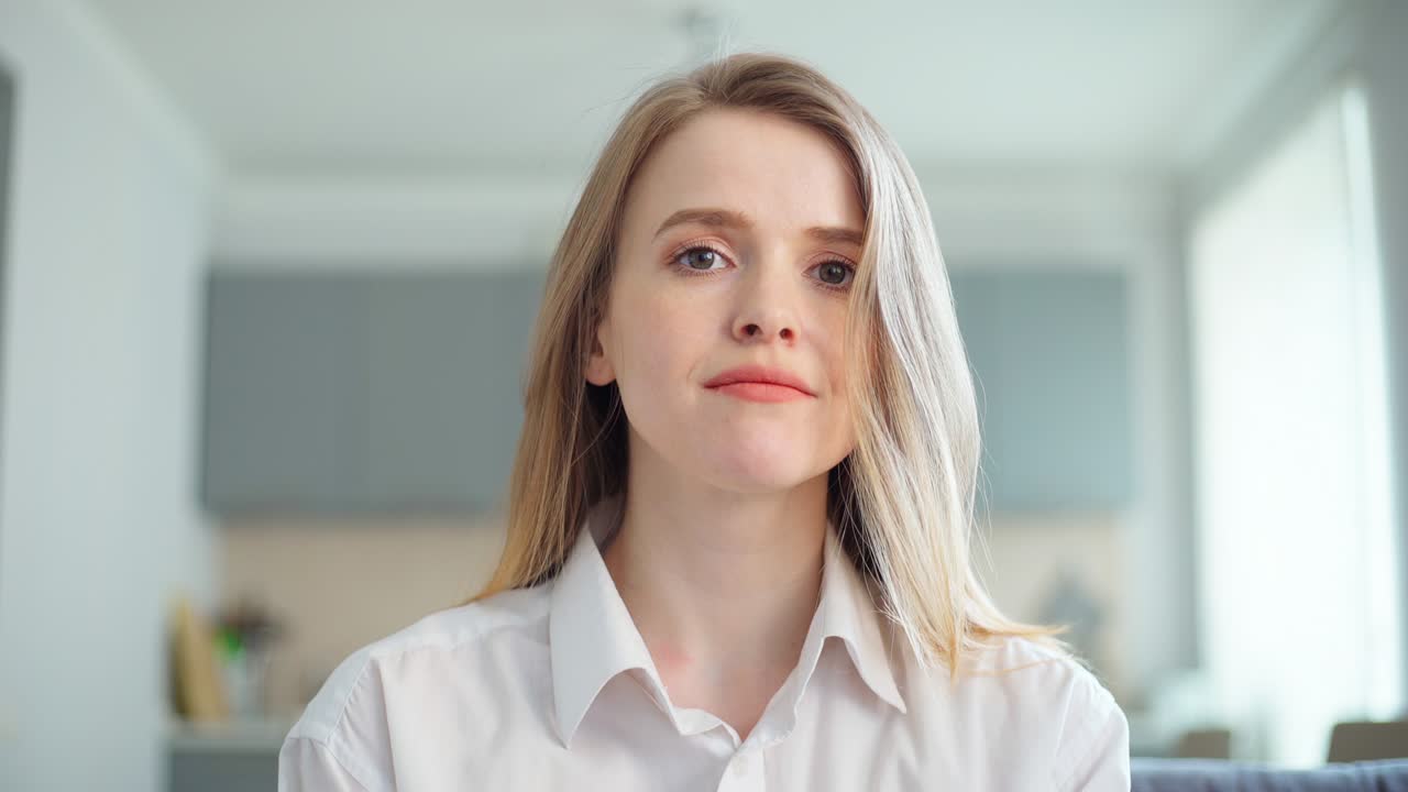 POV of beautiful young woman in white short nodding head and smiling at camera during video conference. Businesswoman expressing agreement during video call or online job interview from home