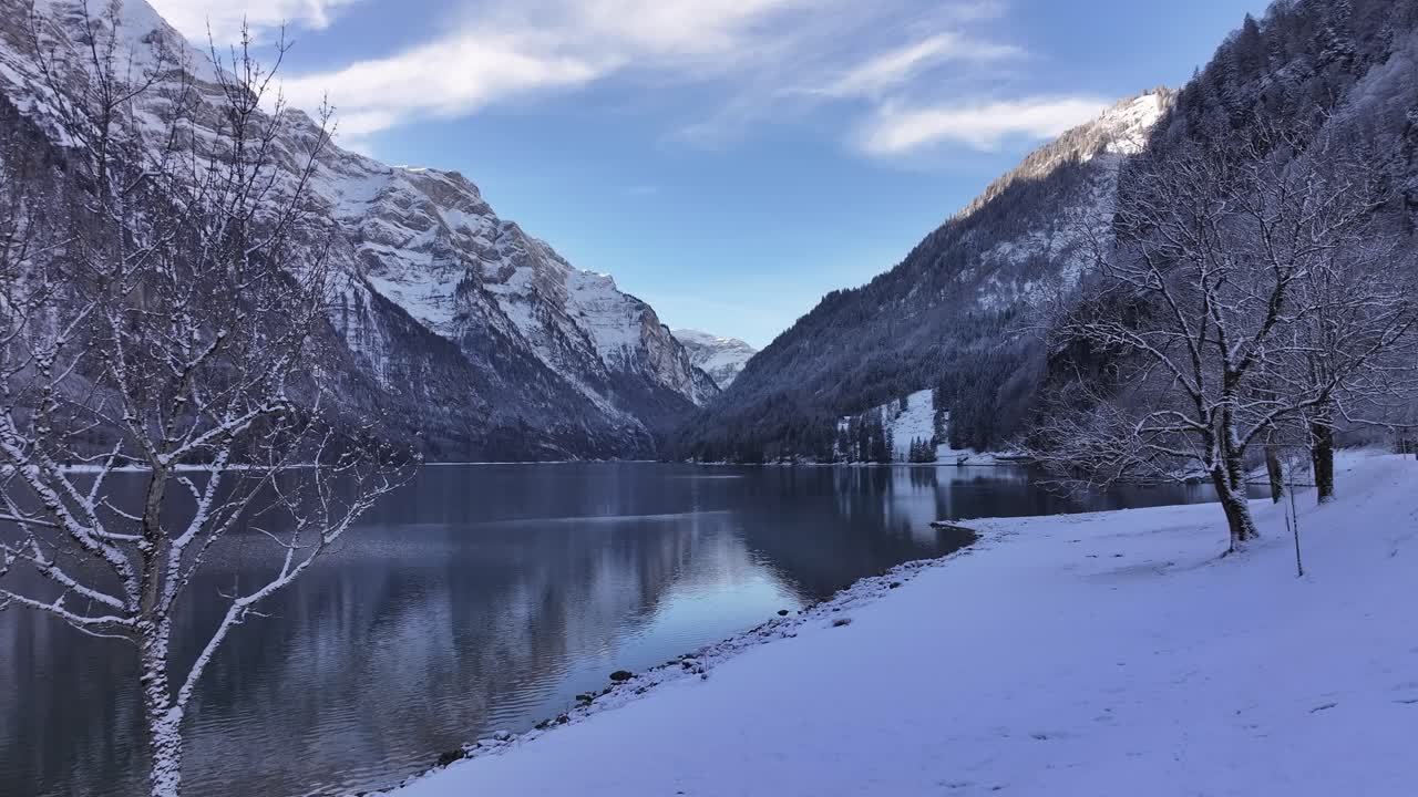 Klöntalersee, stunning Swiss lake in alps during serene winter setting, drone view, snowy landscapes, calm waters and breathtaking mountains.