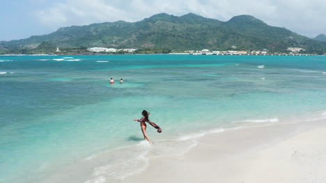 travel vacation concept, tourist woman in bikini soaks up beach and ocean views, drone pan left