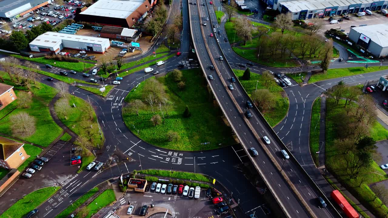 Luftfoto fra fugleperspektiv af Millbrook flyover-rundkørslen i Southampton, Hampshire, England. Optaget ved solnedgang om vinteren med skarpt lys, der skinner, mens bilerne passerer over den industrielle forstad.