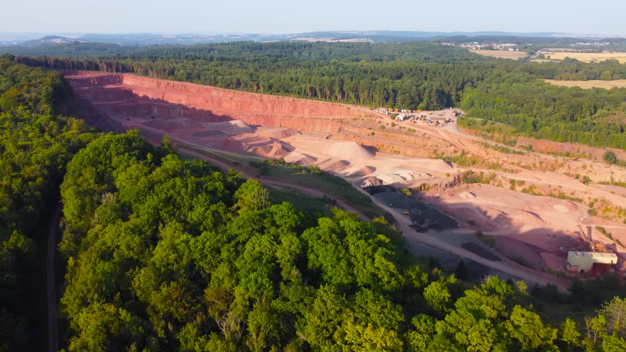 Pushing Aerial Over Quarry in Forest of Dean with Pine Trees Lined Around with Different Layers of Excavation. Heavy Mining Excavating Industry Surrounded by Natural Environment