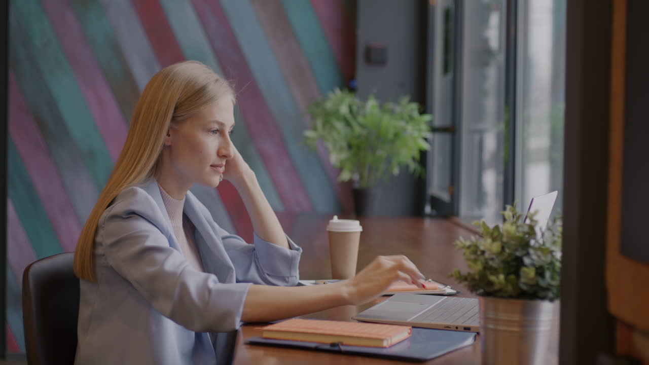 Женщина работает на ноутбуке в кафе