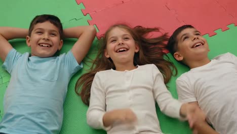 three happy children laughing together on a colorful mat