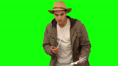 man orienteering with a map and a compass on green screen