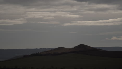 Niedrige-Graue-Wolken-Werfen-Schatten-über-Einsame-Hügel,-Zeitraffer