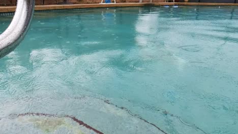 rain drops falling into beautiful clear blue pool at florida home