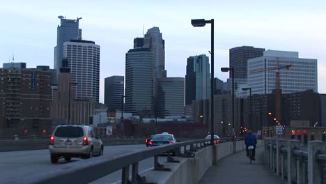 Cars-And-A-Bicyclist-Cross-A-Bridge-Into-The-City