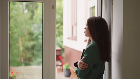 woman observes tranquil scene of rain behind window. businesswoman struggles to keep emotions in check while devastating news threatening to unravel composure