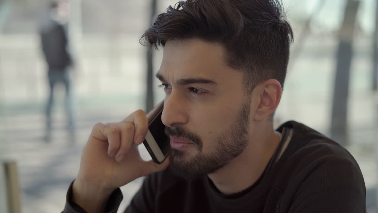 스마트폰으로 말하는 미소 짓는 수염이 있는 남자