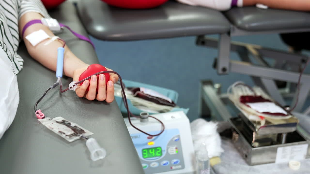 Medical machines are waving the plastic bags with donor blood. Female lies beside with the catheter attached to her arm.