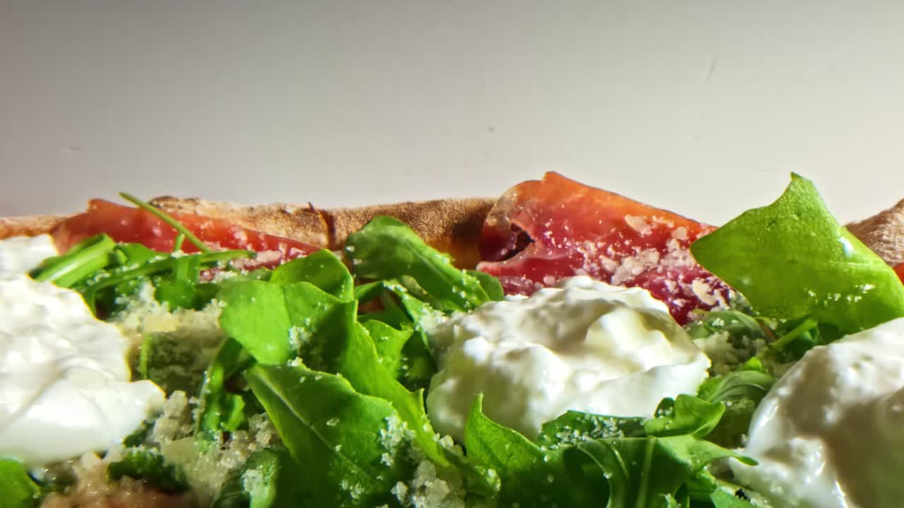 Close-up of pizza topped with arugula, burrata, and grated cheese