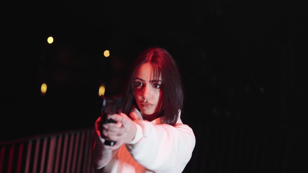 young beautiful woman holds gun in both hands. dramatic scene, dark environment
