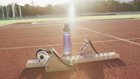 Starting-blocks,-bottle-of-water-and-headphones-lying-on-race-tracks