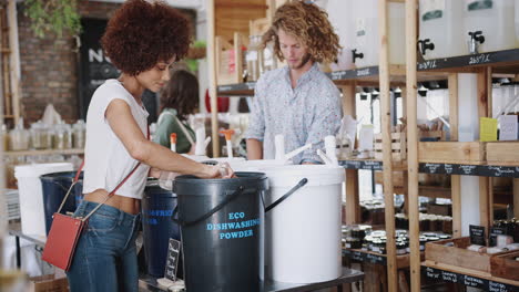 woman filling container with dishwasher powder in plastic free grocery store
