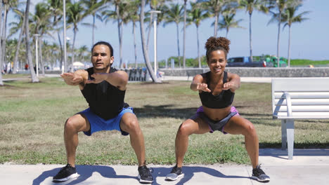 athletic couple knee bending in sunny park