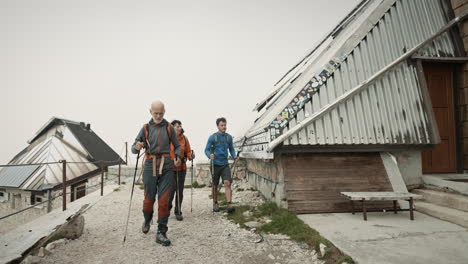 hikers with backpacks and hiking poles arriving at the mountain cottage