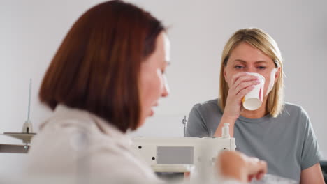 Elegant women relaxing during breakfast, eating shawarma and sipping fruit juice while engaging in cheerful conversation in cozy workspace, sharing ideas, laughing, and bonding over morning meal