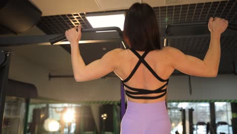 woman doing pull-ups in a gym