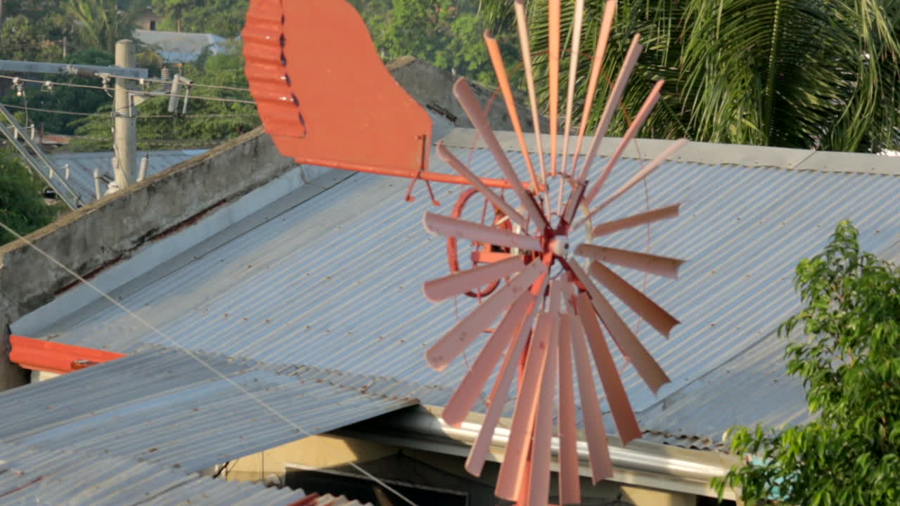 배경에 양철 지붕이 있는 녹슨 회전 풍차