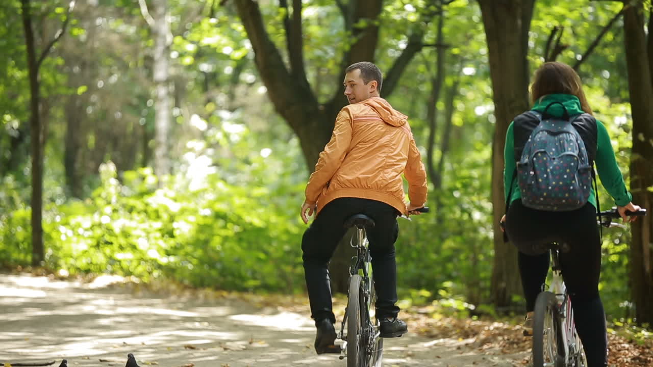 Couple Of Romantic Lovers Cycling. Young couple in love riding a bicycle in park
