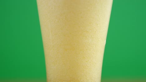 close up view of a fizzing pint of beer for st patrick on green background