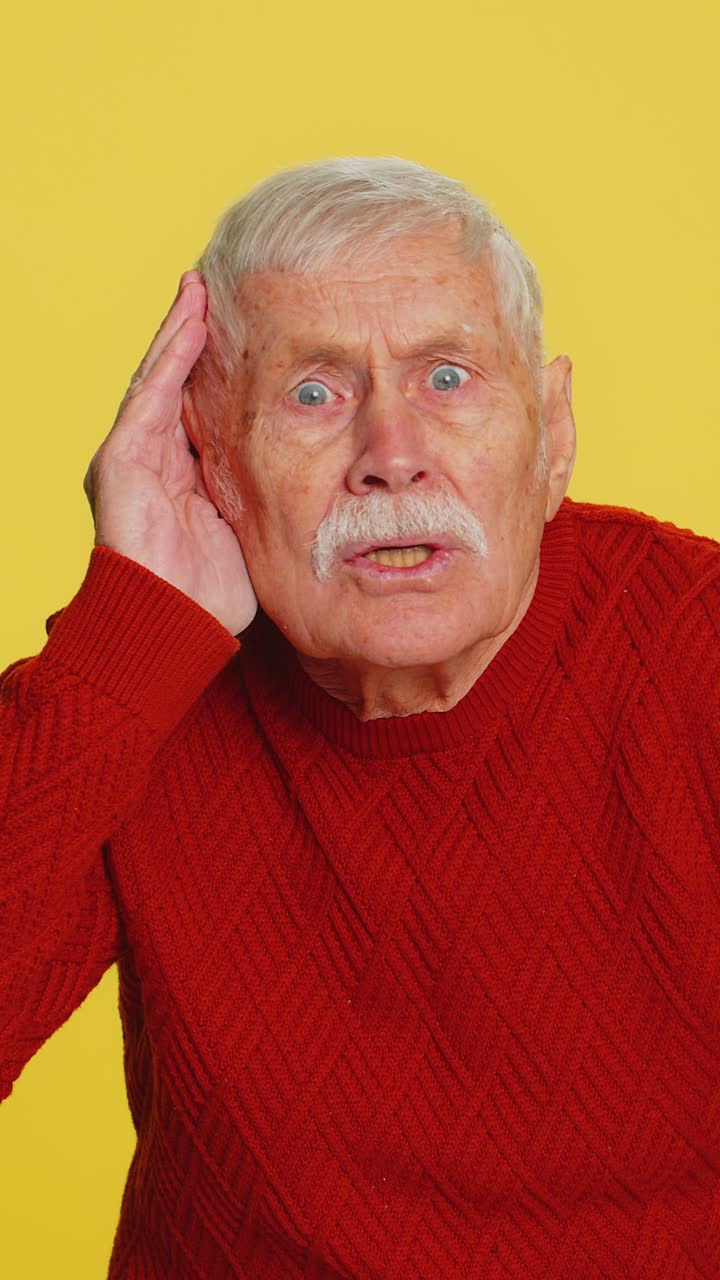 Senior old man trying hear you looking confused and frowning keeping arm near ear for louder voice