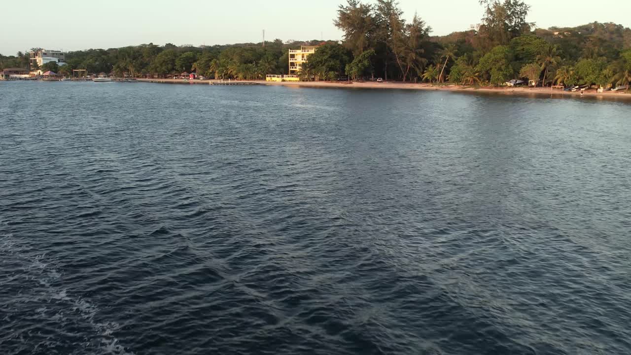 Drone che vola sopra un motoscafo sulla superficie limpida del mare blu con barriera corallina e si muove verso la terraferma