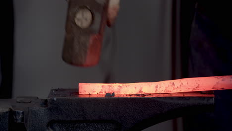 blacksmith shaping red hot iron on the anvil